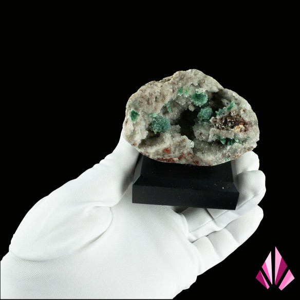 Kolwezite specimen with green spherical aggregates in matrix, displayed in hand on a black stand